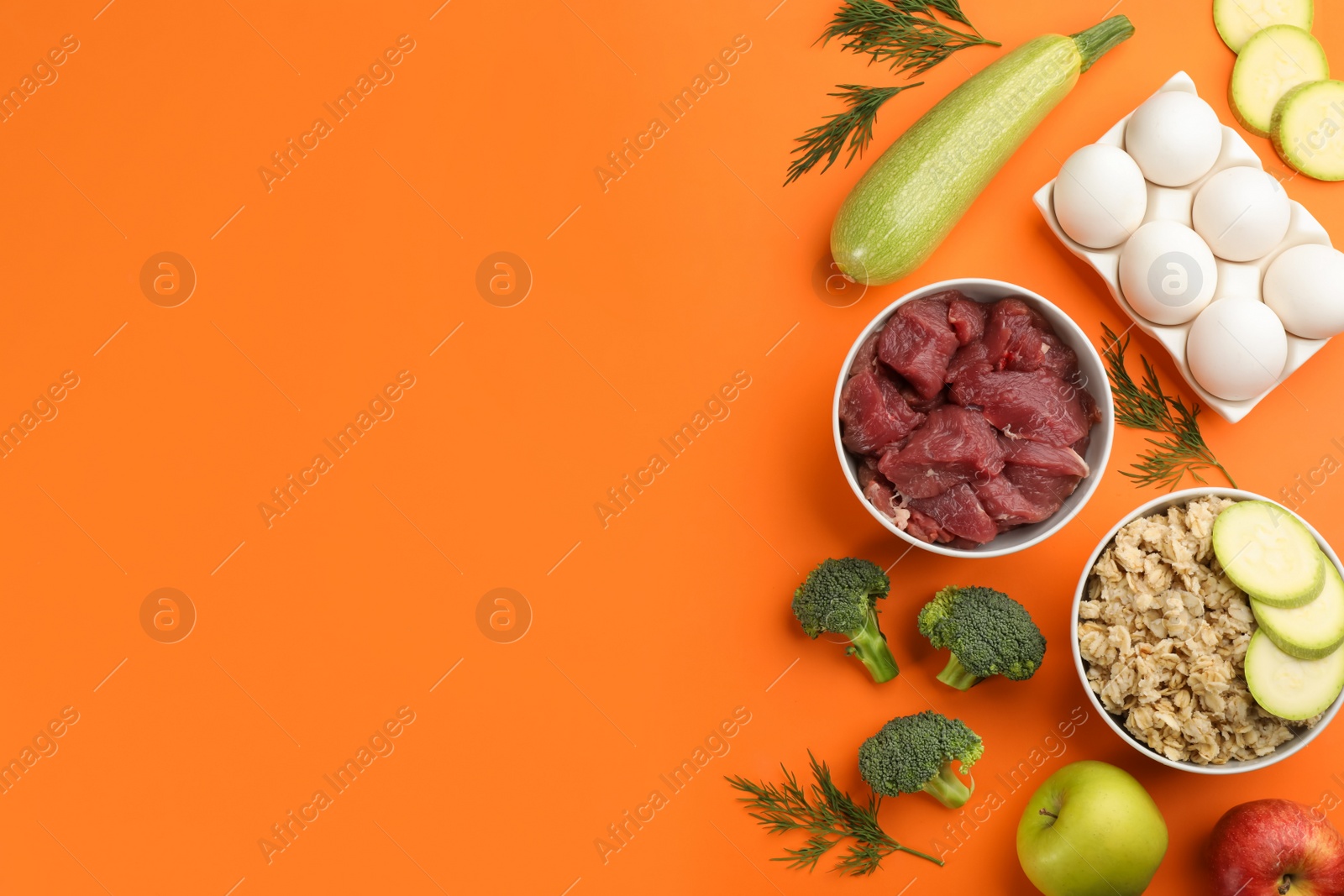 Photo of Pet food and natural ingredients on orange background, flat lay. Space for text