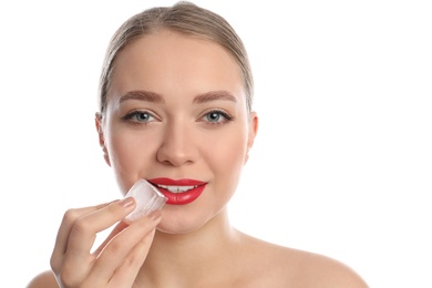 Photo of Young woman with ice cube on white background. Skin care