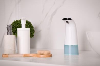 Modern automatic soap dispenser on countertop in bathroom