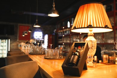 Wooden box with bottle of wine on counter in bar, space for text