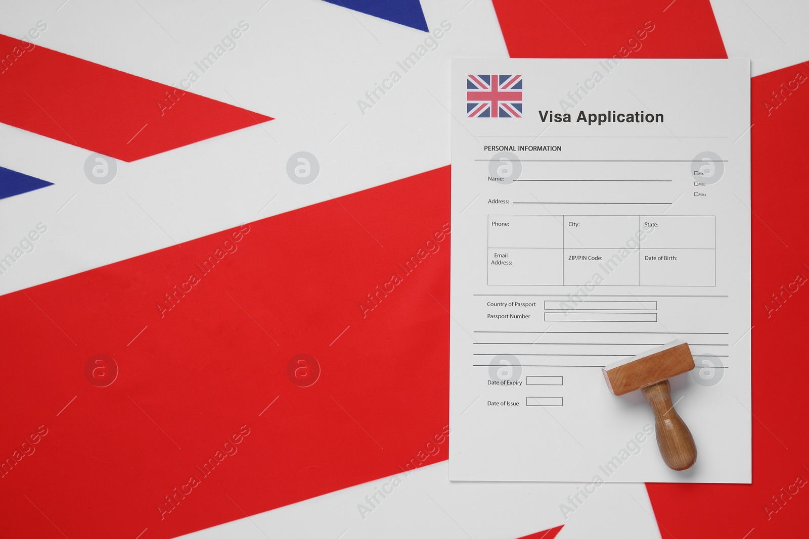 Photo of Immigration to United Kingdom. Visa application form and wooden stamp on flag, top view. Space for text