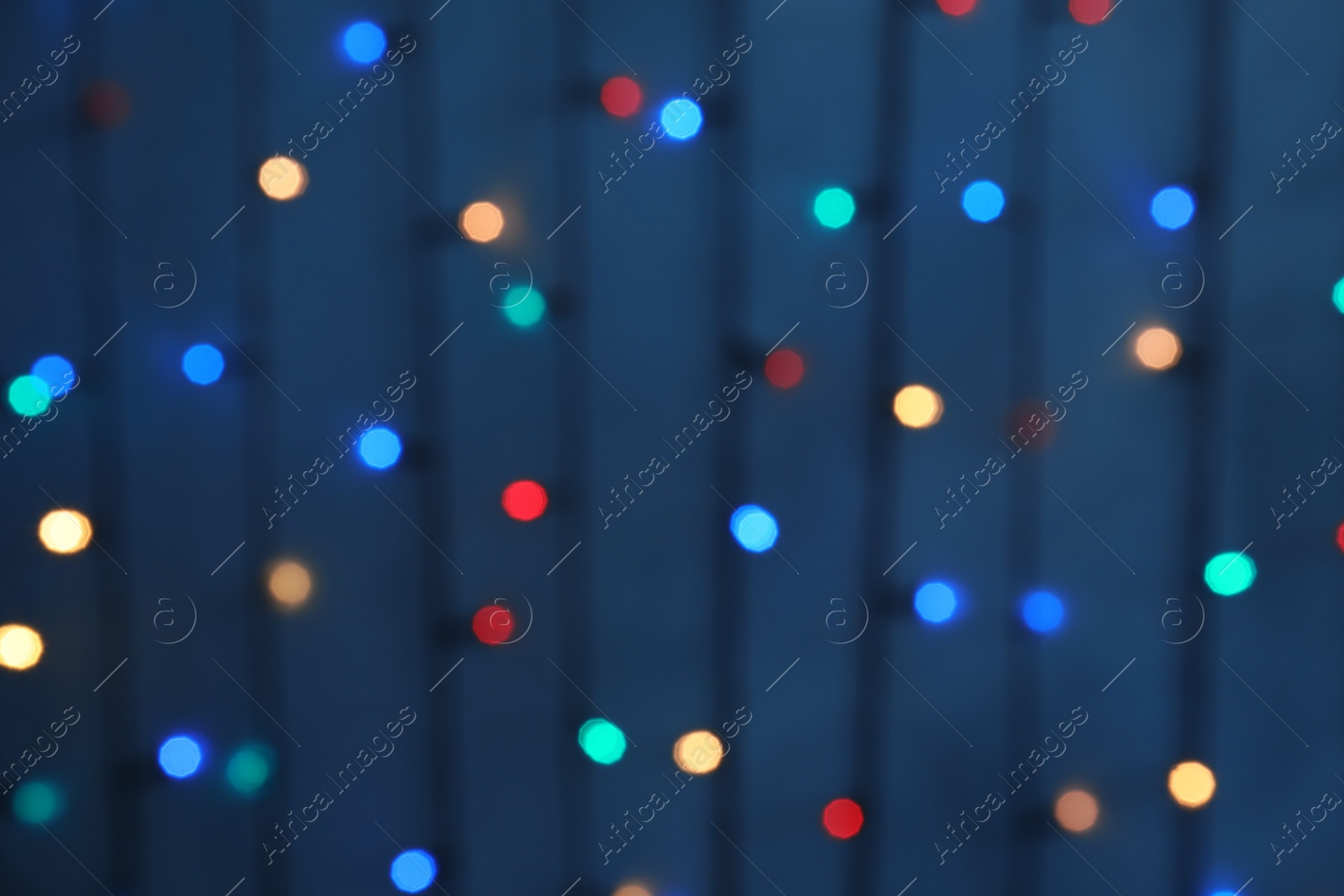 Photo of Blurred view of Christmas lights on color background