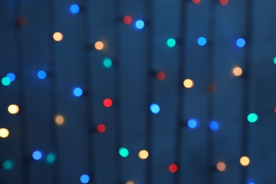 Blurred view of Christmas lights on color background