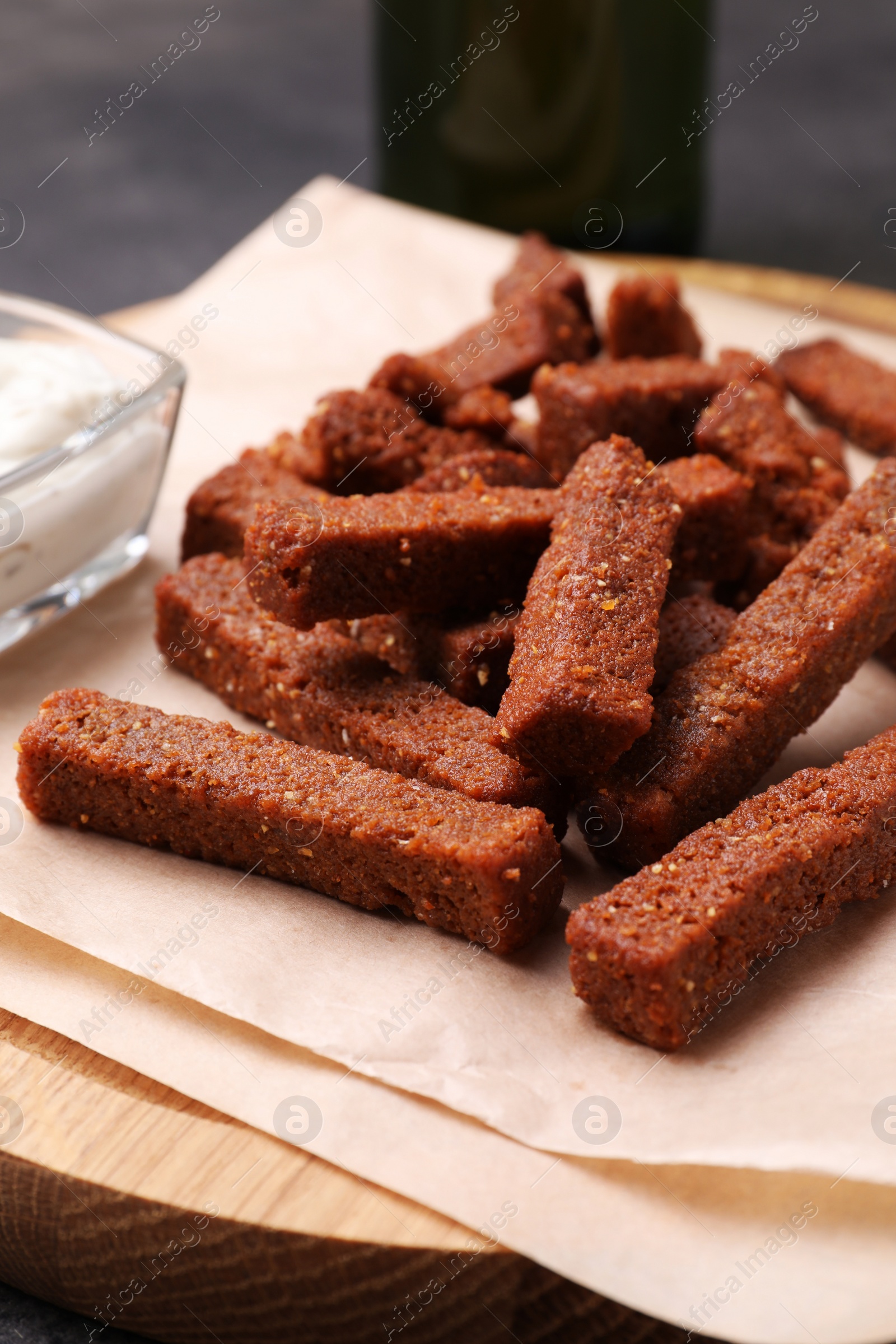 Photo of Crispy rye rusks on wooden board, closeup