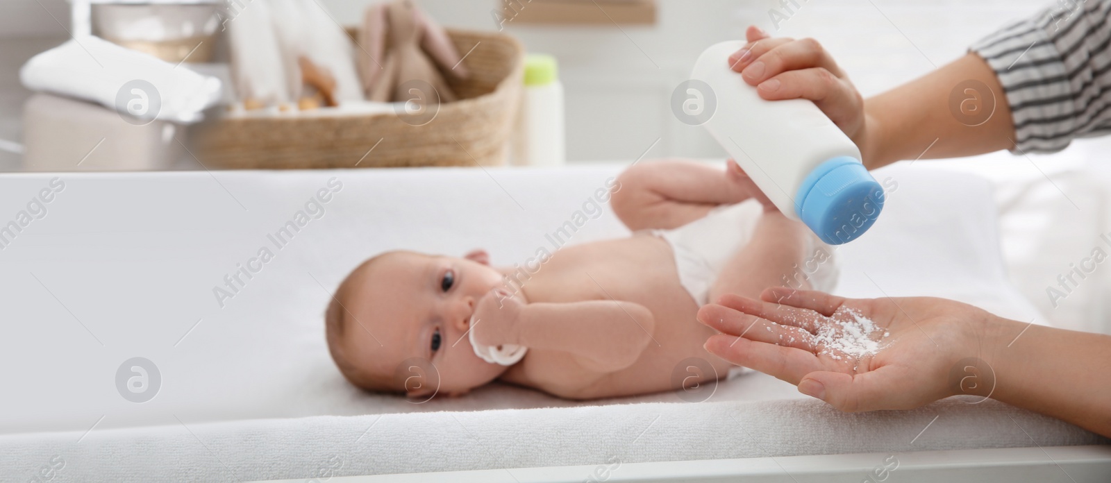 Image of Mother with bottle of dusting powder near her cute baby at home. Banner design