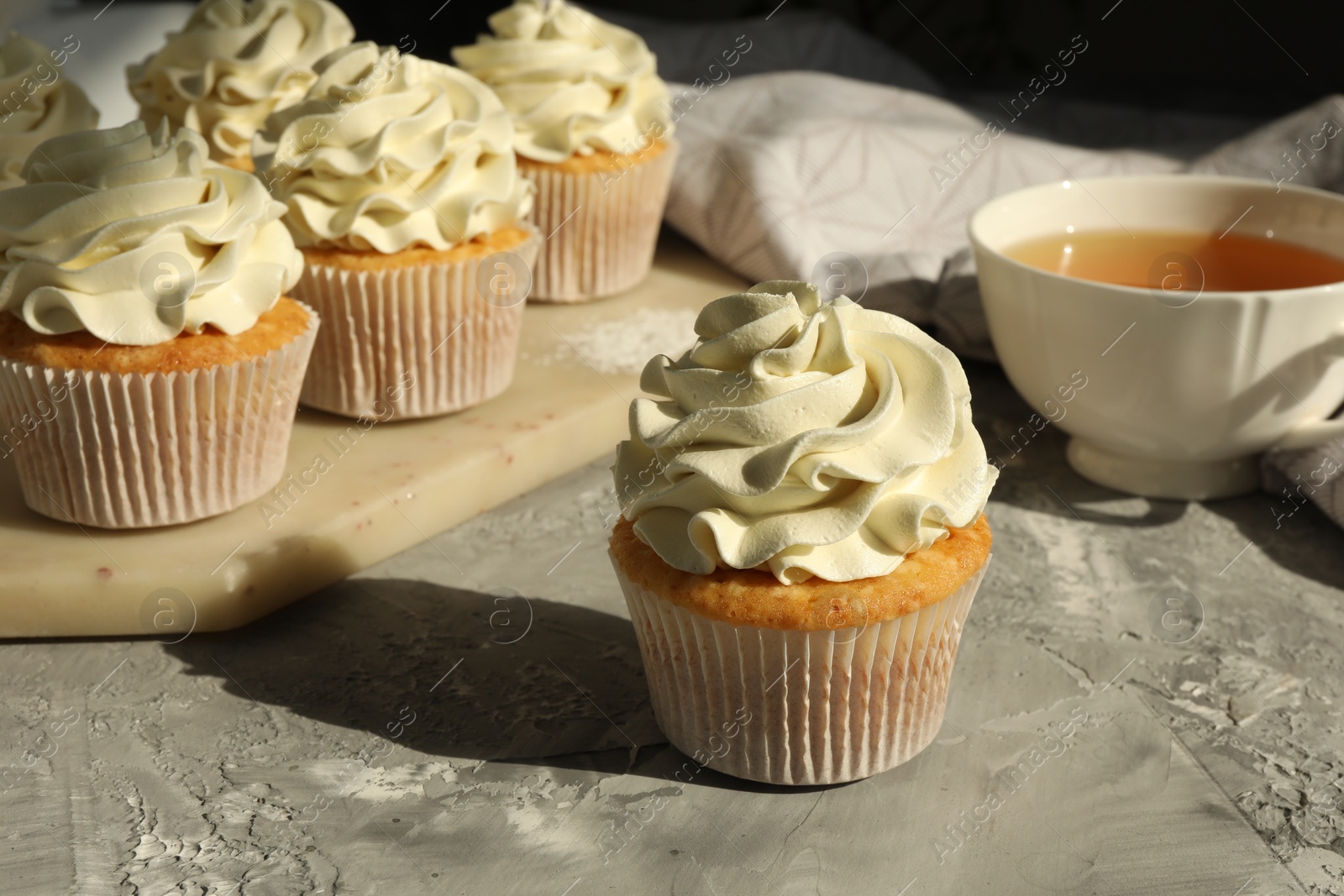 Photo of Tasty cupcakes with vanilla cream on grey table, closeup