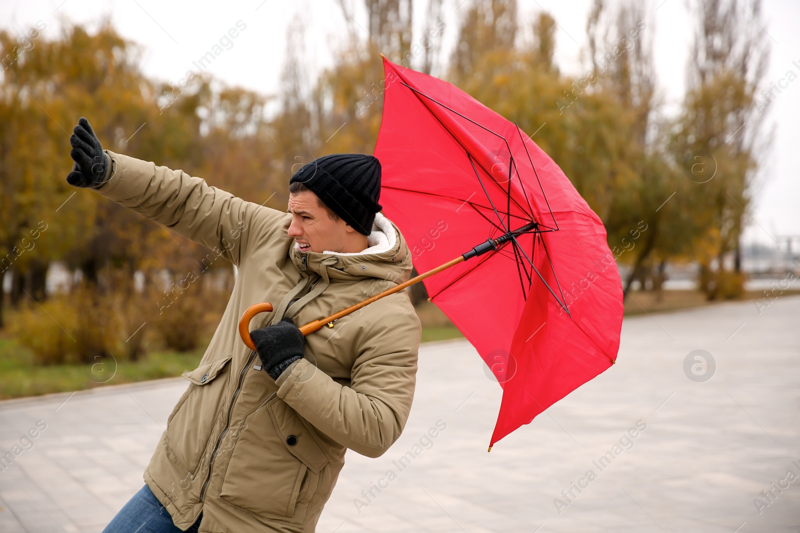 Photo of Man with red umbrella caught in gust of wind outdoors