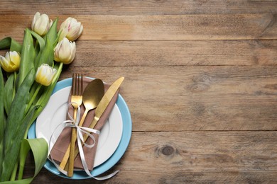 Photo of Stylish table setting with cutlery and tulips on wooden background, flat lay. Space for text