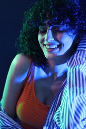 Photo of Beautiful young woman posing on color background in neon lights, closeup