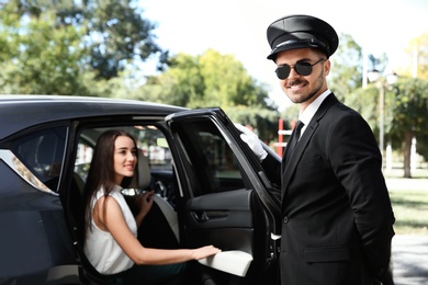 Handsome driver opening car door for young businesswoman. Chauffeur service