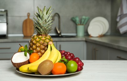 Photo of Plate with different ripe fruits on white wooden table in kitchen. Space for text