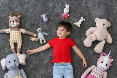 Cute little boy and soft toys on floor, top view