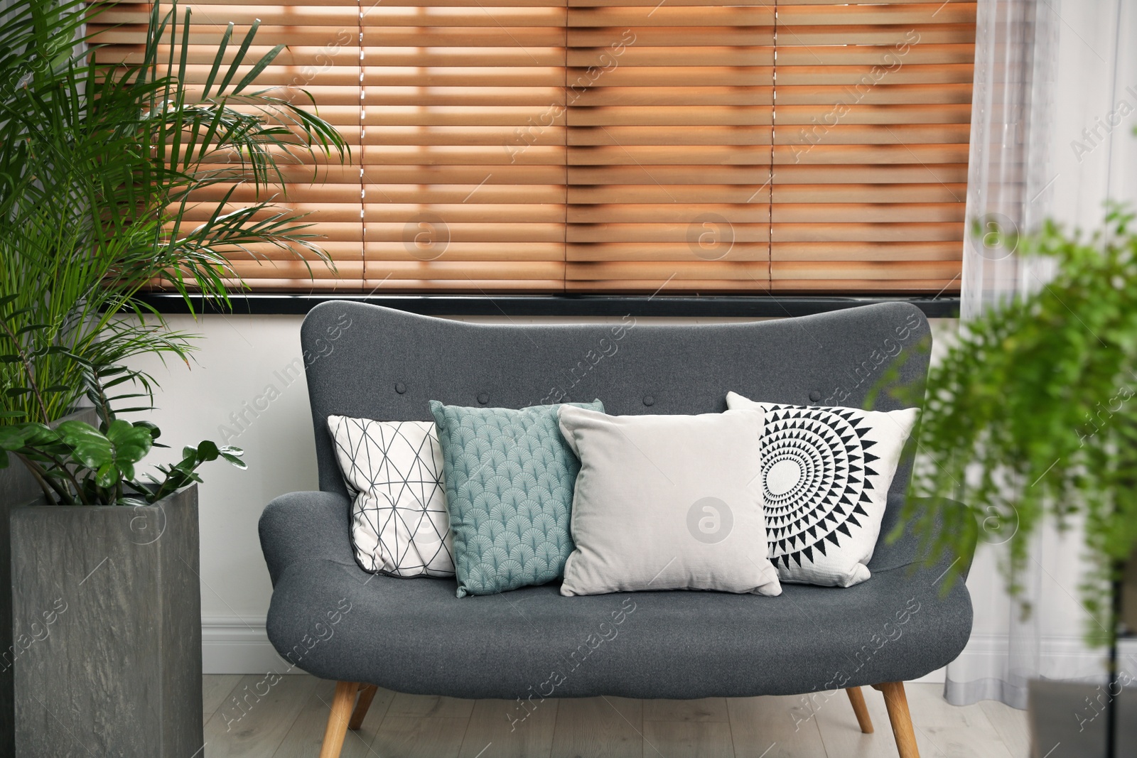 Photo of Stylish decorative pillows on grey couch indoors