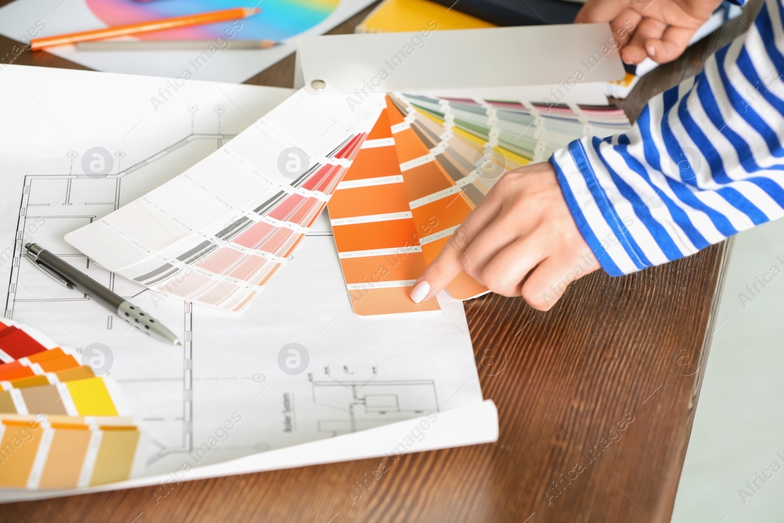 Photo of Female designer working with color palette samples at table