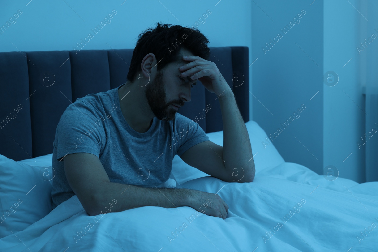 Photo of Man suffering from headache in bed at night