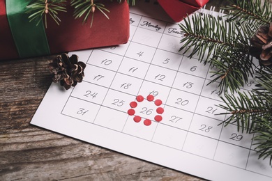 Photo of Calendar with marked Boxing Day date near gifts 
on wooden table, closeup