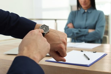 Businessman pointing on wrist watch while scolding employee for being late in office, closeup