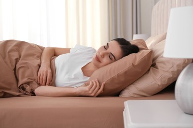 Young woman sleeping in bed with brown linens at home