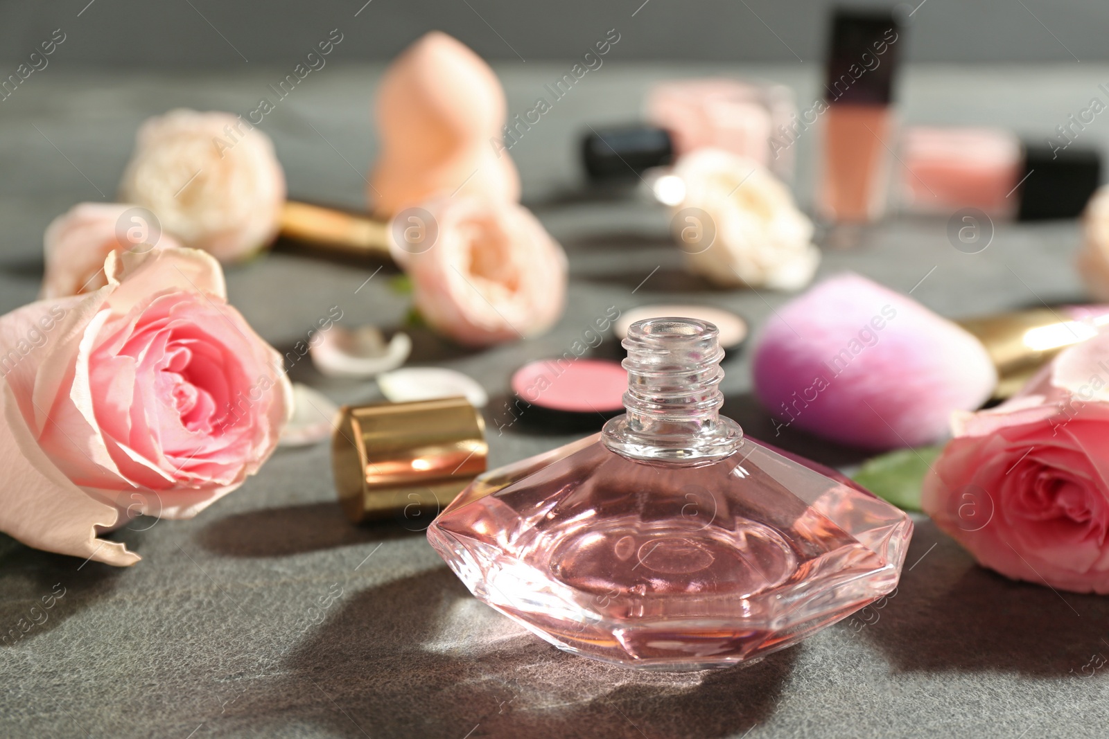 Photo of Beautiful composition with bottle of perfume and roses on grey table