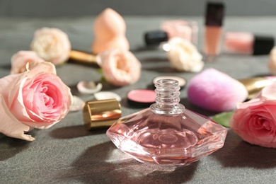 Beautiful composition with bottle of perfume and roses on grey table