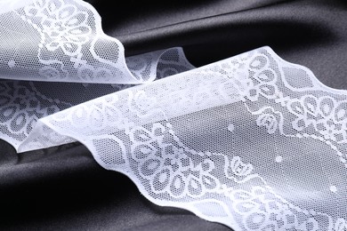 Photo of Beautiful white lace with pattern on black fabric