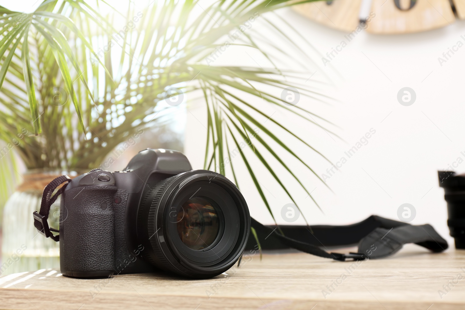 Photo of Professional camera on table against blurred background, space for text. Photographer's equipment