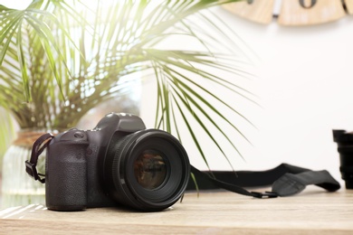 Professional camera on table against blurred background, space for text. Photographer's equipment