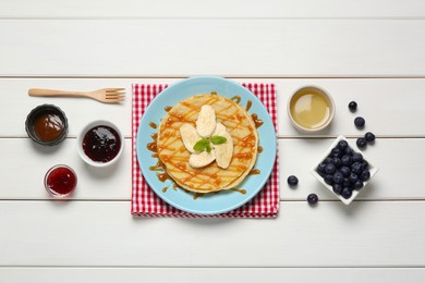 Photo of Delicious crepes with different products on white wooden table, flat lay