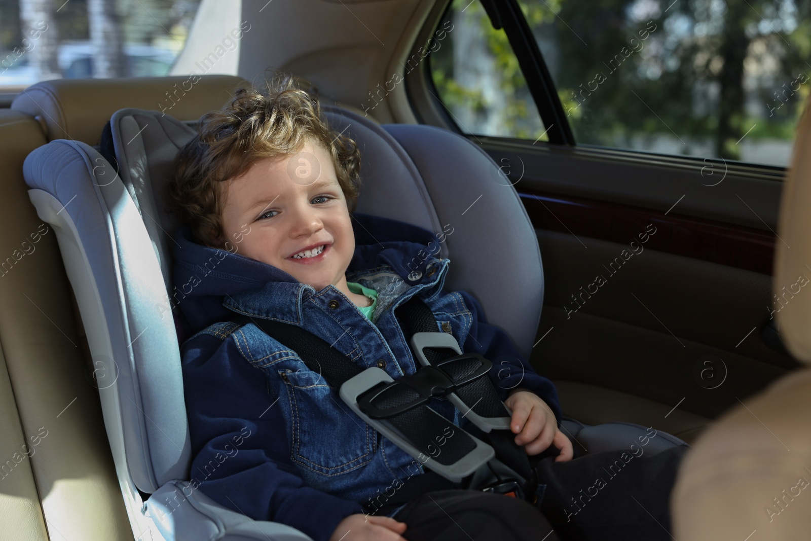 Photo of Cute little boy sitting in child safety seat inside car