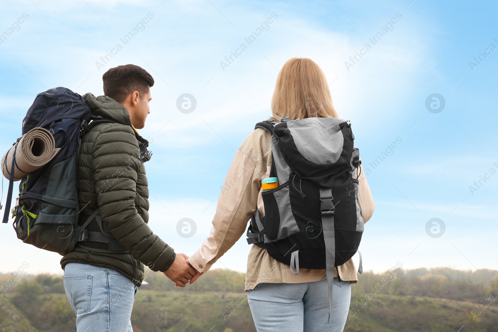 Photo of Couple of hikers with travel backpacks enjoying nature on autumn day, back view