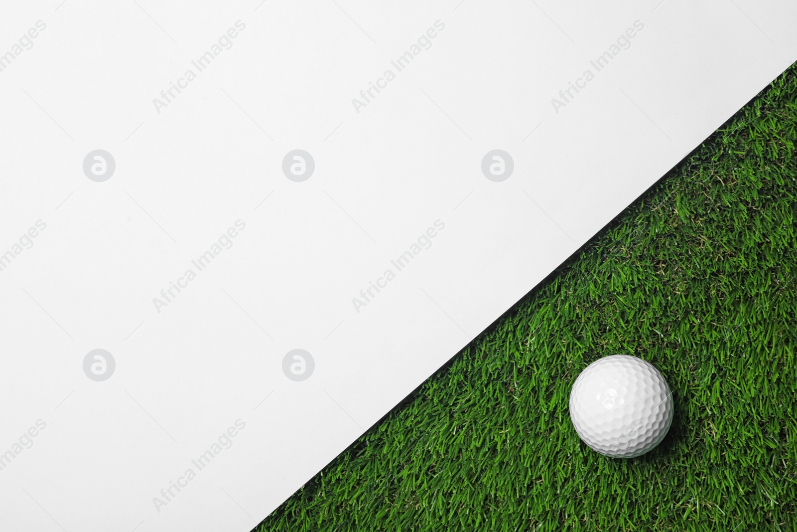 Photo of Golf ball and white paper on green artificial grass, top view with space for text