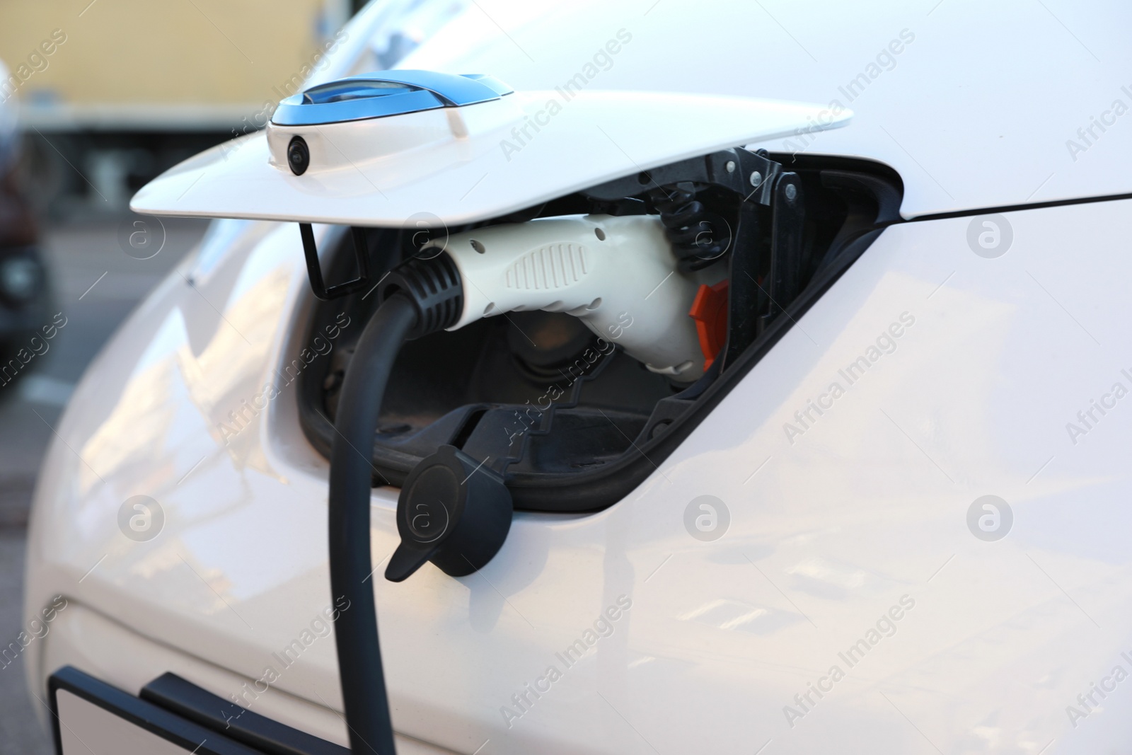 Photo of Charging modern electric car from station outdoors, closeup