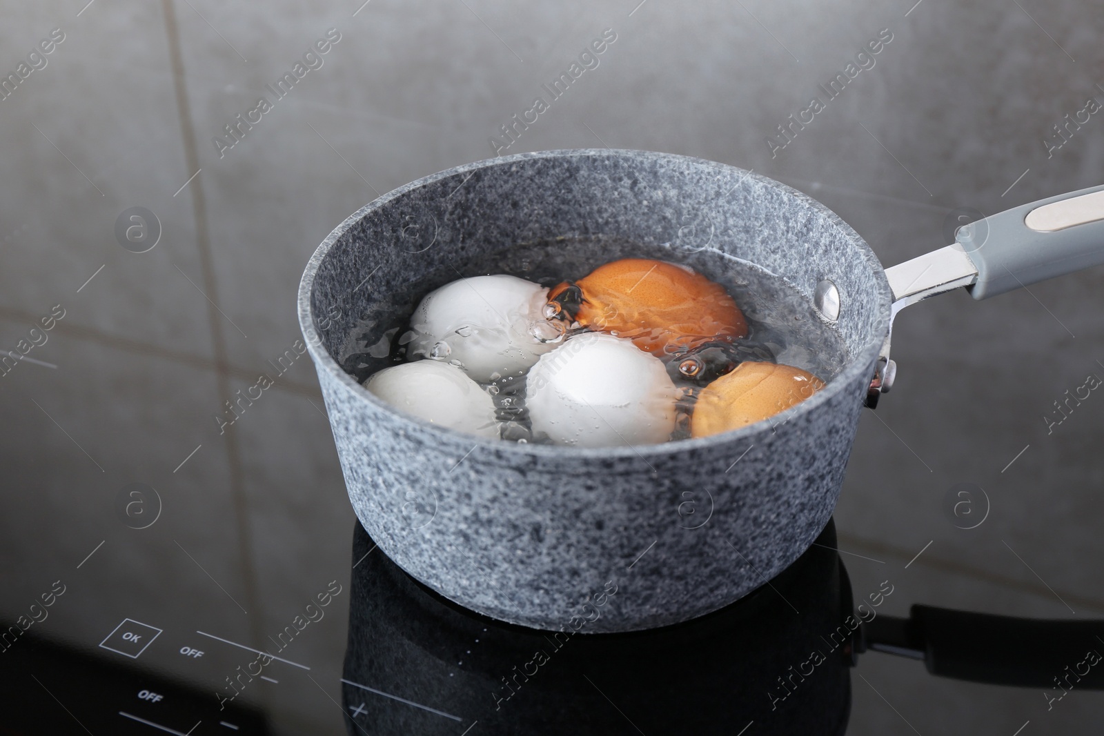 Photo of Chicken eggs boiling in saucepan on electric stove