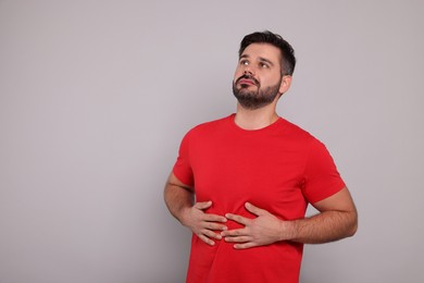 Photo of Man suffering from stomach pain on grey background, space for text