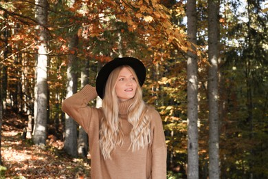 Portrait of beautiful young woman with hat in autumn forest