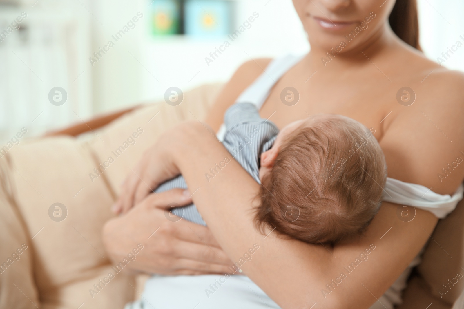 Photo of Young woman breastfeeding her baby at home, closeup