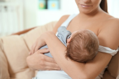 Young woman breastfeeding her baby at home, closeup