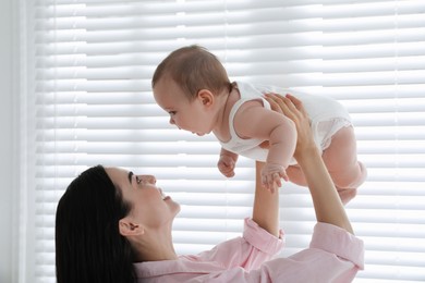 Young mother playing with her little baby at home