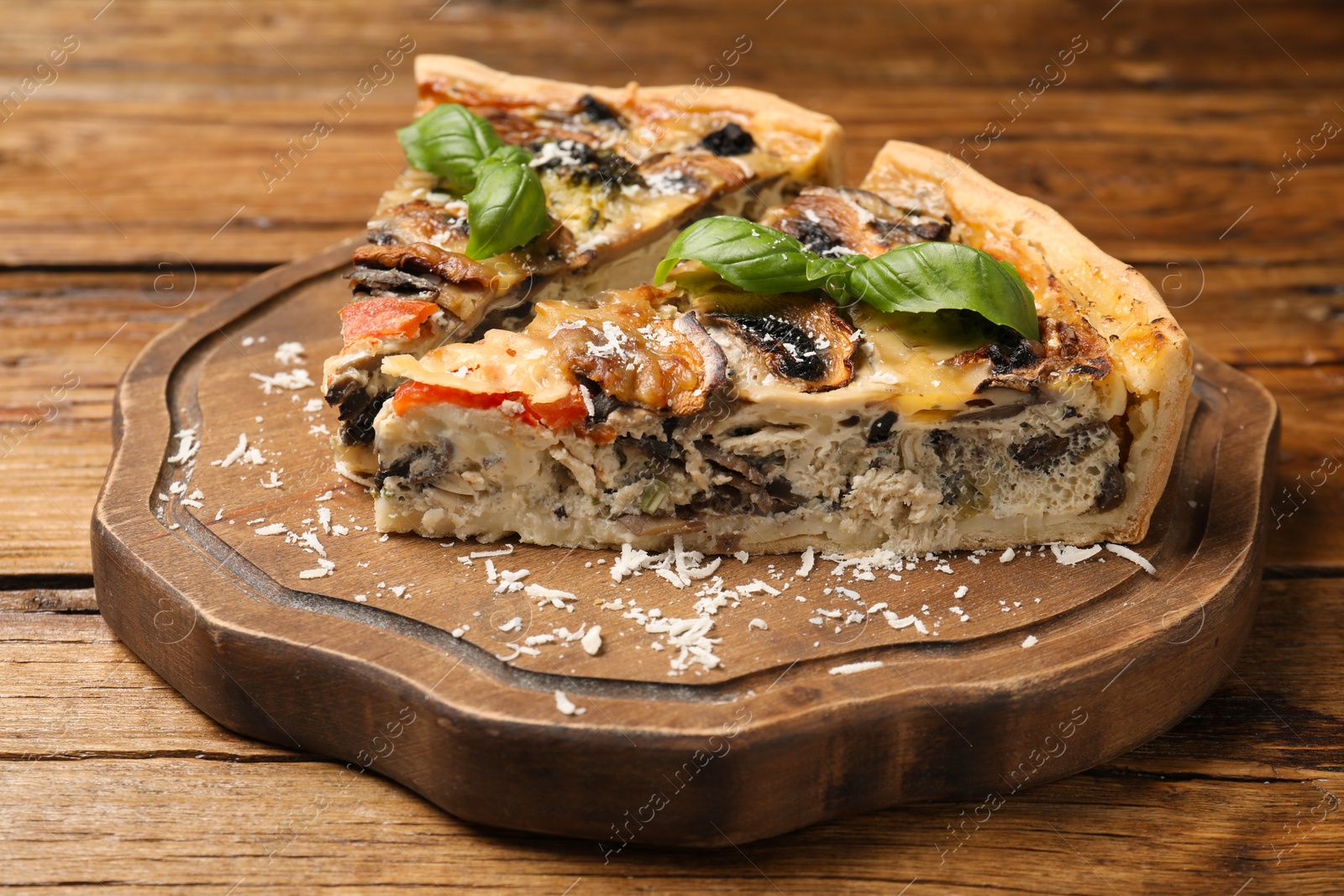 Photo of Pieces of delicious quiche with mushrooms on wooden table, closeup