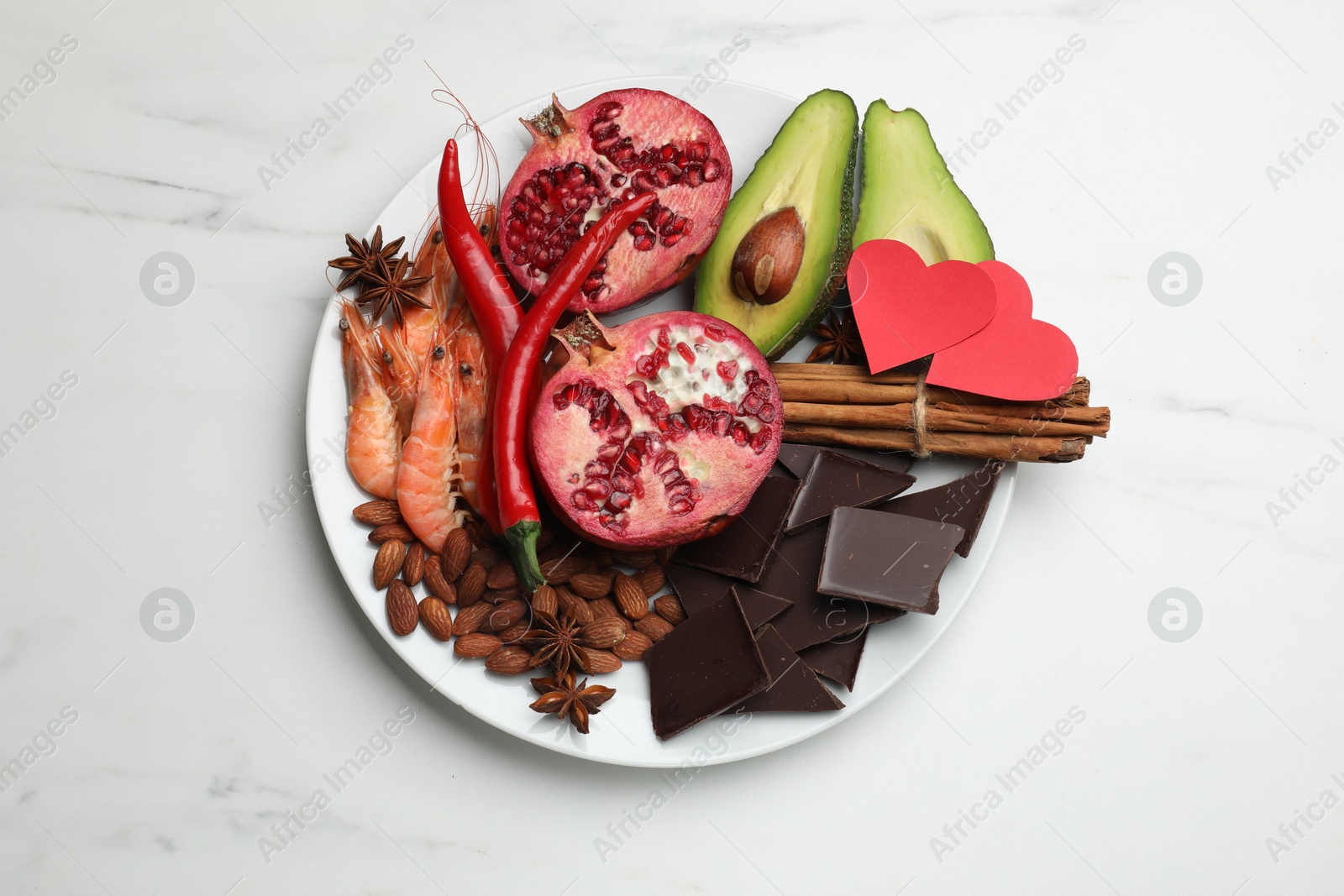 Photo of Natural aphrodisiac. Different products and paper hearts on white marble table, top view