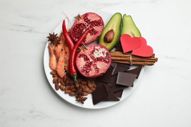 Photo of Natural aphrodisiac. Different products and paper hearts on white marble table, top view