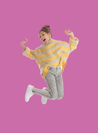 Image of Happy cute girl jumping on pink background