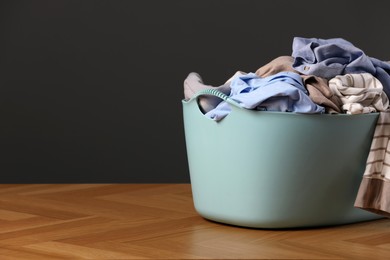 Photo of Laundry basket with clothes near dark grey wall. Space for text