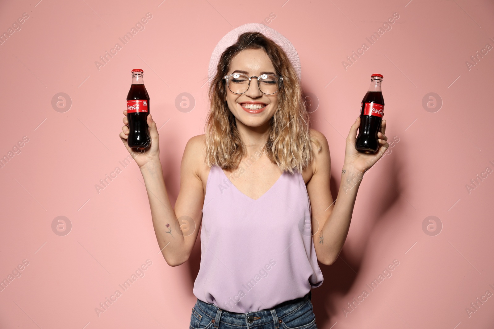 Photo of MYKOLAIV, UKRAINE - NOVEMBER 28, 2018: Young woman with bottles of Coca-Cola on color background