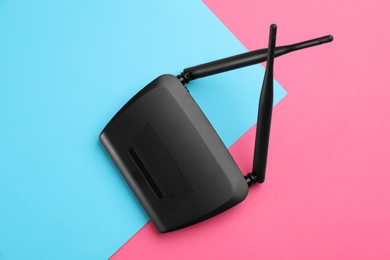 Modern Wi-Fi router on color background, top view