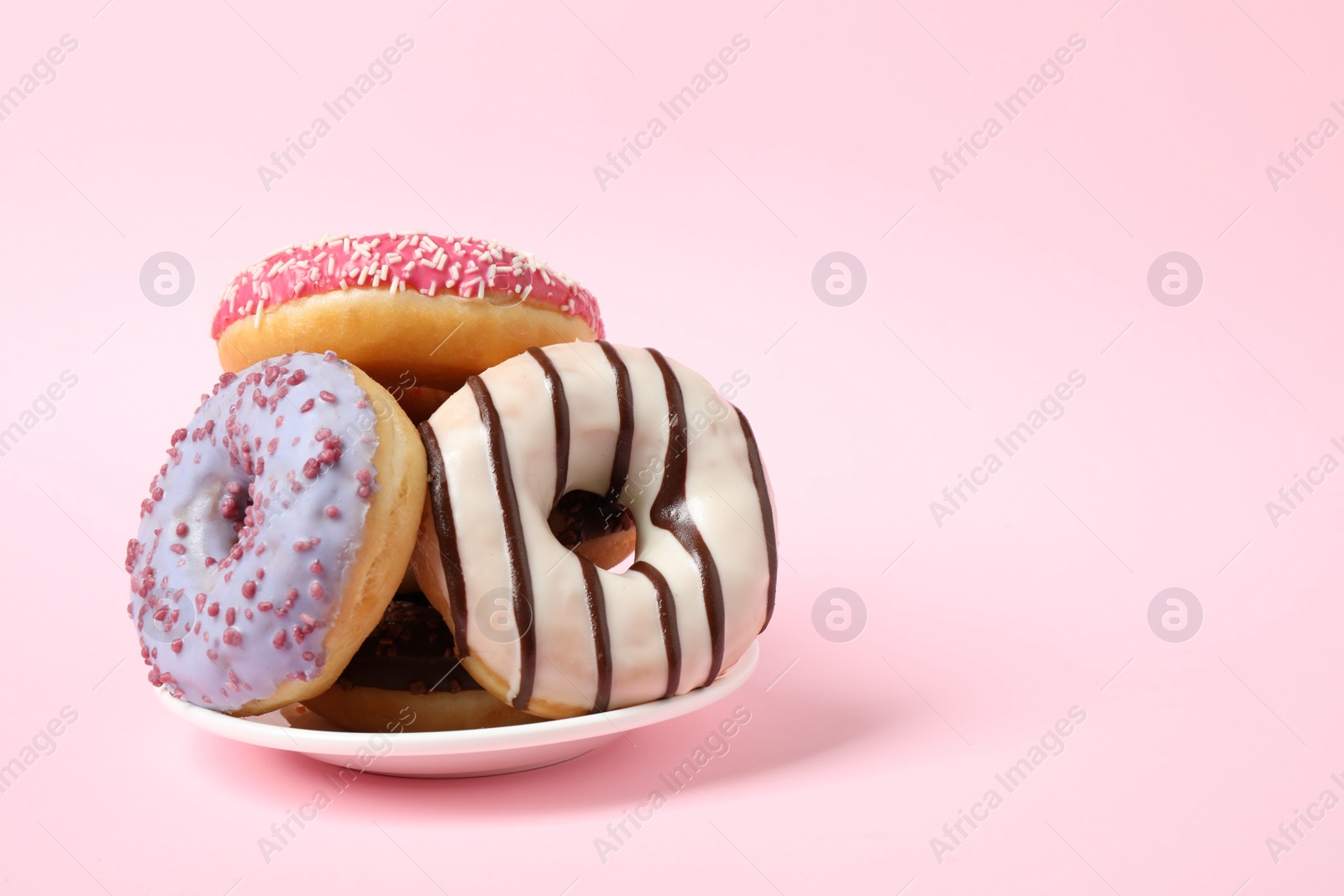 Photo of Tasty glazed donuts on pink background, space for text