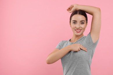 Photo of Beautiful young woman doing breast self-examination on pink background, space for text