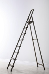 Modern metal stepladder near white wall indoors