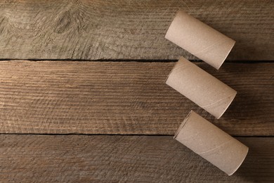 Photo of Empty toilet paper rolls on wooden table, flat lay. Space for text