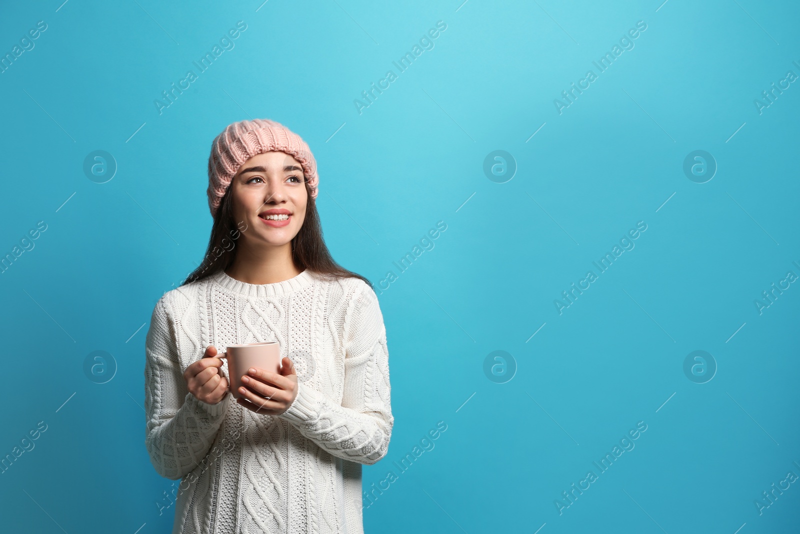 Photo of Young woman in sweater with cup of hot coffee on color background, space for text. Winter season